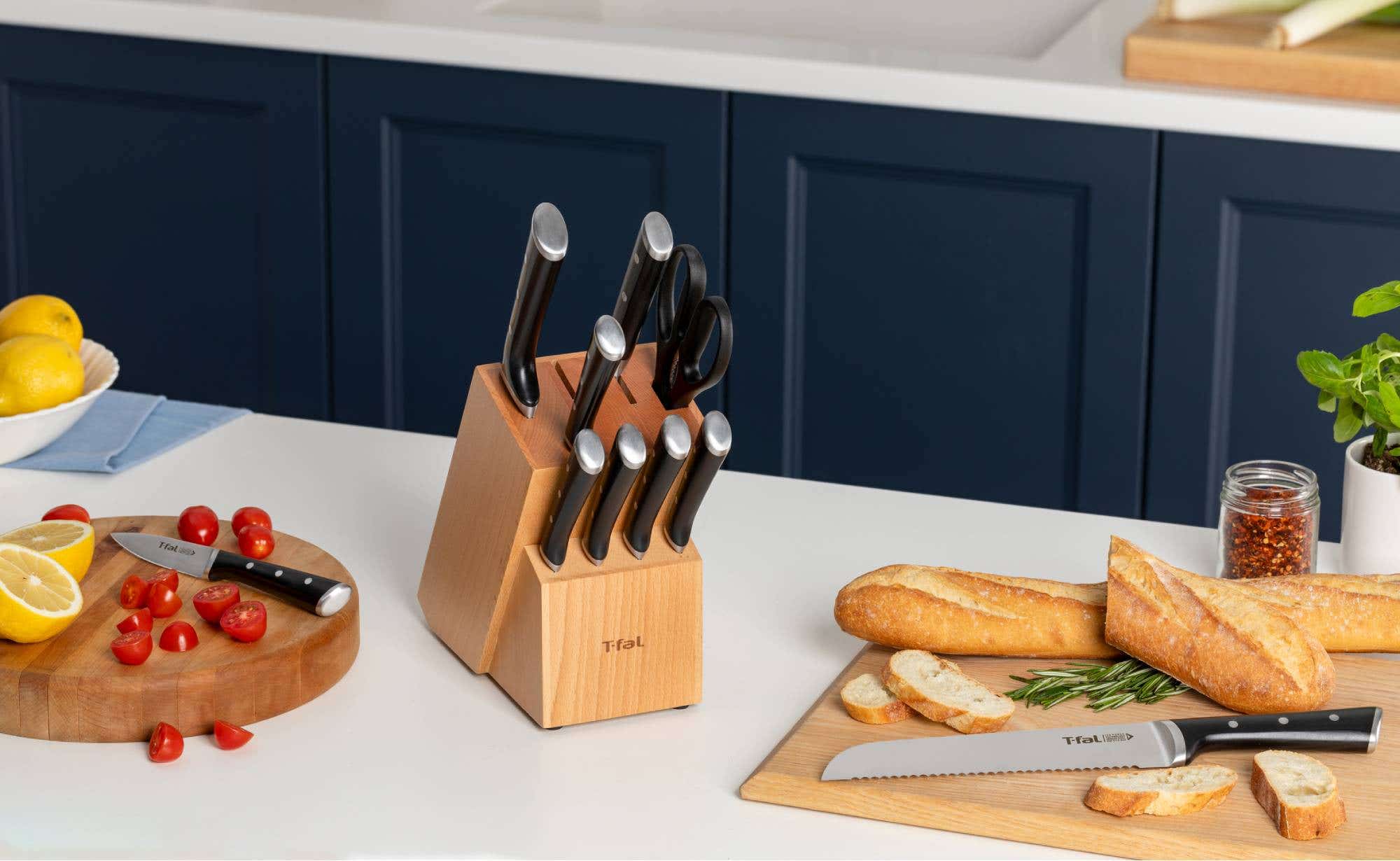 A cutting board with a T-fal knife, displaying a pan filled with chicken, colorful vegetables, and sliced oranges.